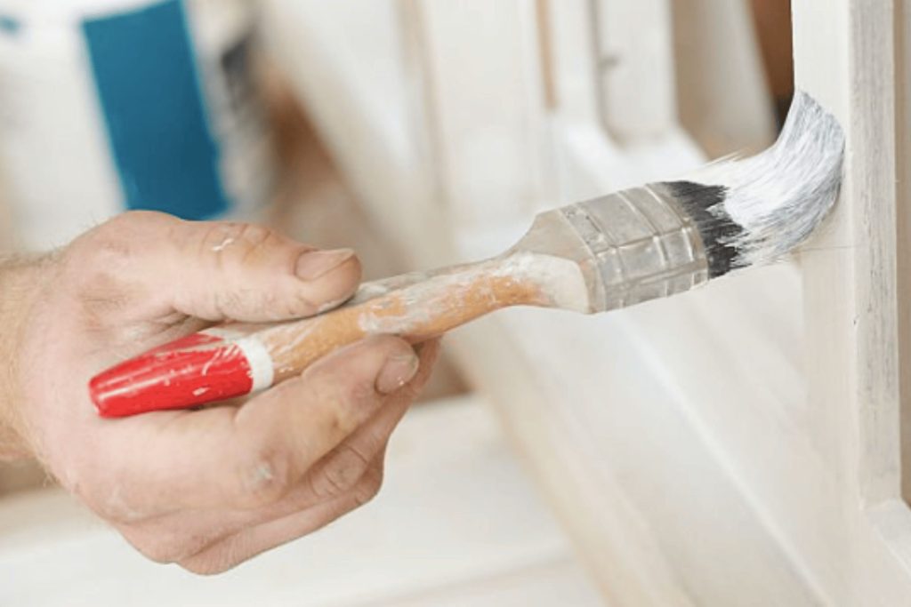 A close up of a man painting UPVC windows with a hand brush