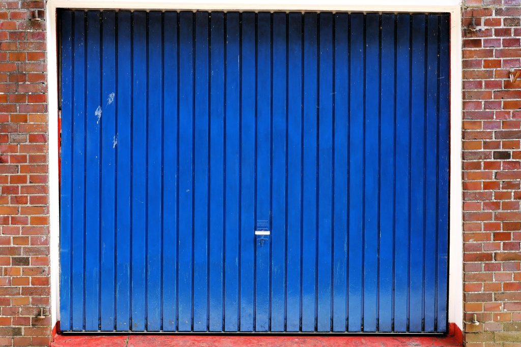 An old and worn blue garage door in Swansea that needs to be spray painted