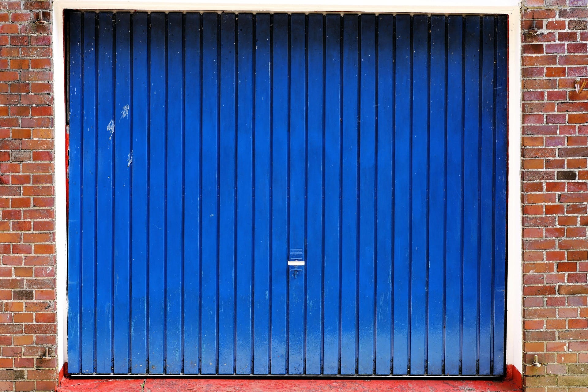 An old and worn blue garage door in Swansea that needs to be spray painted